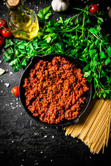 Canvas Print - Bolognese sauce in a frying pan with pasta dry and parsley. 