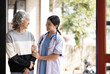 © wichayada - Young caregiver helping senior woman walking. Nurse assisting her old woman patient at nursing home. Senior woman with walking stick being helped by nurse at home.