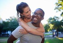 Love, Interracial Or Couple Of Friends Piggy Back In A Park On Fun Romantic Date In Nature Bonding Together. Relaxing, Black Man Or Happy Woman Laughing Or Enjoying Quality Time On A Holiday Vacation