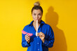 Young woman tasting chewing gum against yellow background