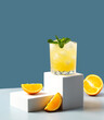 Fresh cocktail with orange, mint and ice, selective focus. Classic lemonade with orange. Modern still life with podium. Freshness beverage for festive party. Summer holiday cocktail.