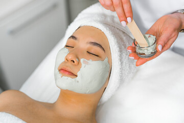 Wall Mural - Young beautiful Asian getting an face massage and green algae mask. High quality photo