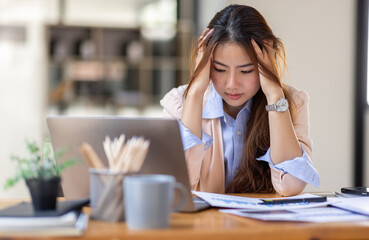Wall Mural - Young business Asian women are stressed while working on laptop, Tired asian businesswoman with headache at office, feeling sick at work copy space in workplace an home office.