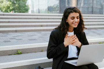 Wall Mural - Young businesswoman using laptop while sitting on stairs outdoors