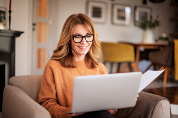 Wall Mural - Attractive woman sitting at home and using laptop for work