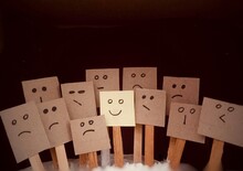 Positive Attitude Concept With Small Notepad Drawing With Many Faces And Standing Out With A Smile. Smile When The Situation Is Bad.