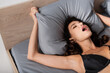 © LIGHTFIELD STUDIOS - High angle view of sensual woman in bra touching pillow on bed at home.