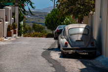 An Old Punch Buggy Sits In The Alleyway On The Island Of Santorini During The Day