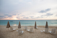 Scenic View Of Parasols And Lounge Chairs At Beach Against Cloudy Sky