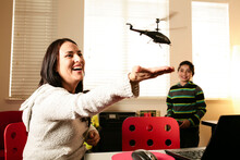 Hispanic Mother And Son Playing With A Remote Controlled Toy Helicopter.