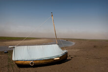 A Boat Sits Grounded At Low Tide In The North Sea Town Of Blakeney, Norfolk, United Kingdom.