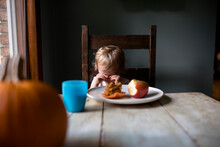 Upset Toddler Girl Sitting At Table Eating A Snack