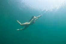 One Girl Dives In The Water Wearing A Red Bikini With White Dots. Tamaulipas, Mexico.