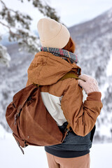 Wall Mural - rear view on young female in coat with backpack travelling alone in winter landscape, in mountains, hiking alone, enjoying the view around. snowy frost winter day. freedom, inspiration concept