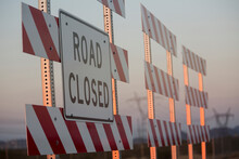 Road Closed Sign On Barricade Against Sky During Sunset