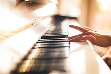 Close Up Image Of Child's Hand Playing Piano In A Sunny Room.