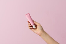 Woman Hand Hold A Blank Cosmetic Container Isolated On Pink.
