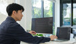 © wattana - Asian male programmer typing data code on laptop and programming on computer in office.