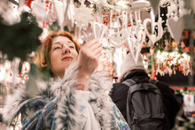 Woman Admiring Christmas Ornament Decorations On The Market