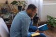 © Demetr White/Stocksy - man on the background of books and flowerpots
