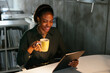 © BONNINSTUDIO/Stocksy - Cheerful businesswoman with cup of coffee using tablet