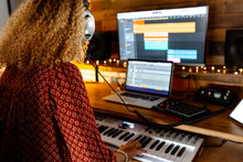 Back Of Music Producer At Home Studio Using Keyboard Controller