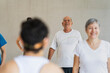 © Leonardo Borges Nuñez/Stocksy - Older adult smiling receiving instructions in yoga class