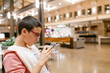 © ByLorena/Stocksy - Teenager using smartphone in shopping center
