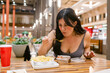 © ByLorena/Stocksy - Woman having lunch in fast court restaurant