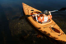 Little Boy In A Kayak Alone And Paddling Independently On A Lake