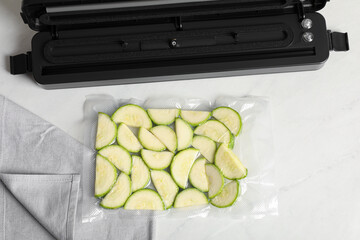 Wall Mural - Sealer for vacuum packing with plastic bag of zucchini on white table, flat lay