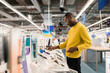 © Hernandez & Sorokina/Stocksy - Man Looking Cellphones In Electronics Shop