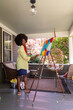 © Raymond Forbes LLC/Stocksy - African American Lifestyle Girl artist Painting easel outdoors