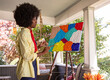 © Raymond Forbes LLC/Stocksy - Elegant Black Lifestyle Girl artist Painting easel in home studio