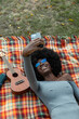 © Raymond Forbes LLC/Stocksy - Beautiful Black Girl Listens to music outdoors on blanket