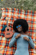 © Raymond Forbes LLC/Stocksy - Beautiful Black Girl Listening to music outside on blanket