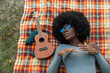 © Raymond Forbes LLC/Stocksy - Beautiful Black Girl Listening to music outdoors on blanket