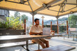 © Alba Vitta/Stocksy - Man working on laptop at outdoor cafeteria