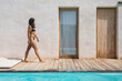 © Bisual Studio/Stocksy - Woman Walking By Pool At Luxury house