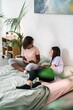 © Studio Marmellata/Stocksy - Happy young diverse ladies talking on bed at home
