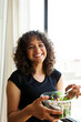 © Valentina Barreto/Stocksy - Cheerful woman eating salad after yoga class
