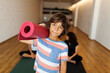 © Valentina Barreto/Stocksy - Boy with mat in yoga studio portrait