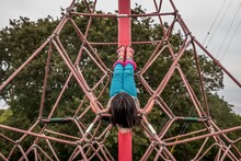 Girl Lying Down On Climbing Rope Structure At A Park
