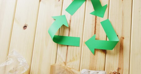 Sticker - Close up of trash and recycling symbol of green paper arrows on wooden background, with copy space