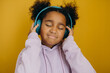 © Stereo Shot/Stocksy - Smiling black girl listening to music in studio