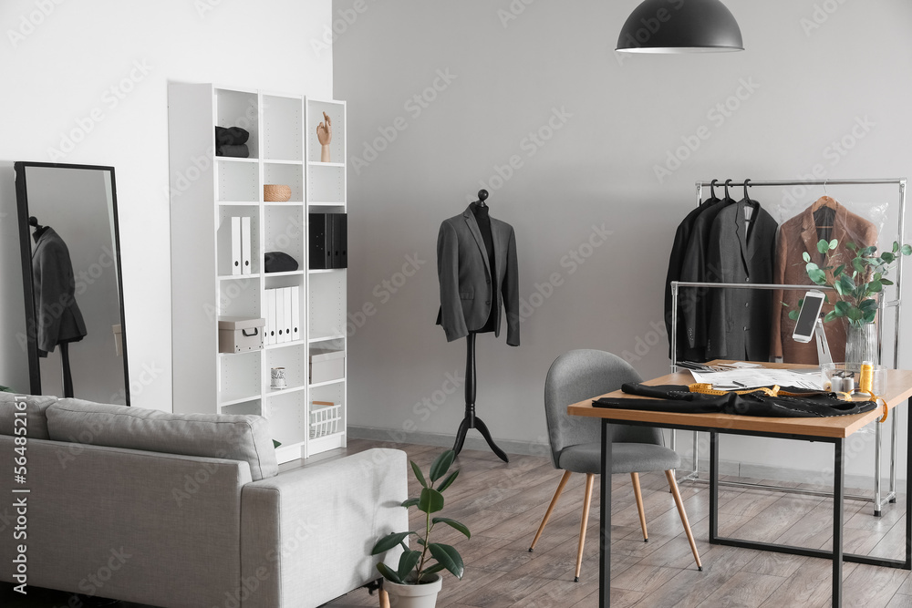 Tailor's workplace with tablet computer and supplies in modern atelier