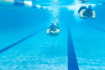 Wall Mural - latin young teenager man swimmer athlete wearing cap and goggles in a swimming underwater training In the Pool in Mexico Latin America	