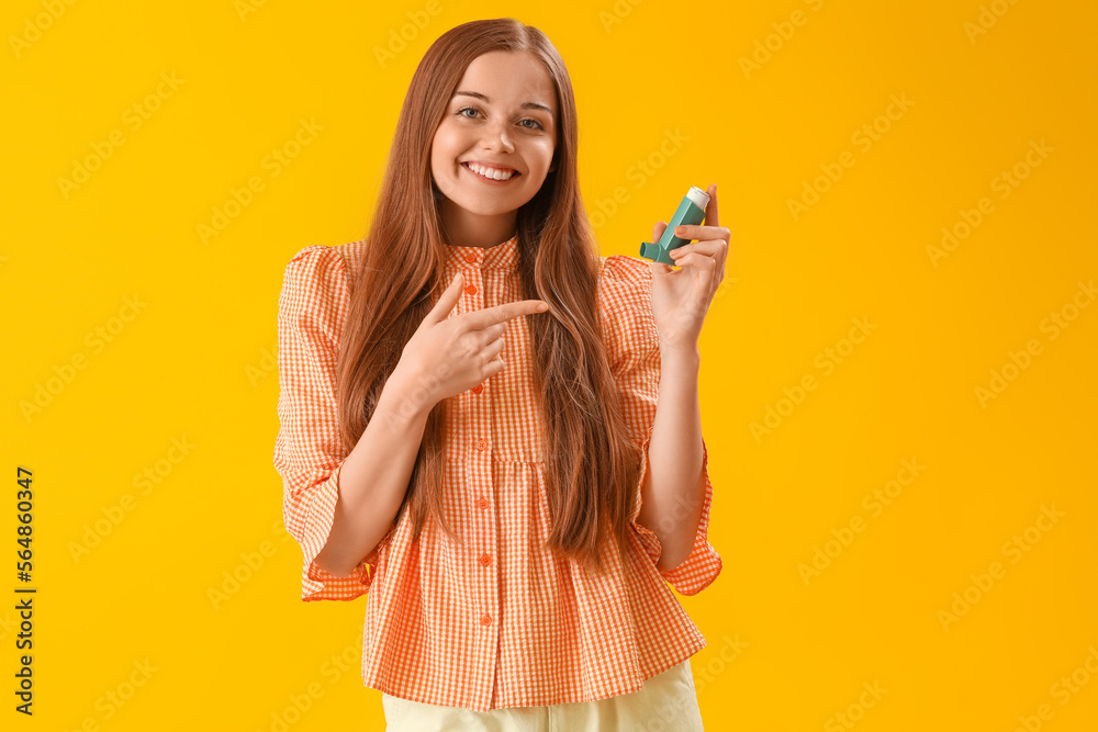Young woman with inhaler on yellow background