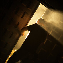 Silhouette Of A Man Exiting A Doorway With Light Rays.