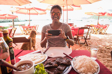 Woman At Beach Restaurant Taking Picture Of Food
